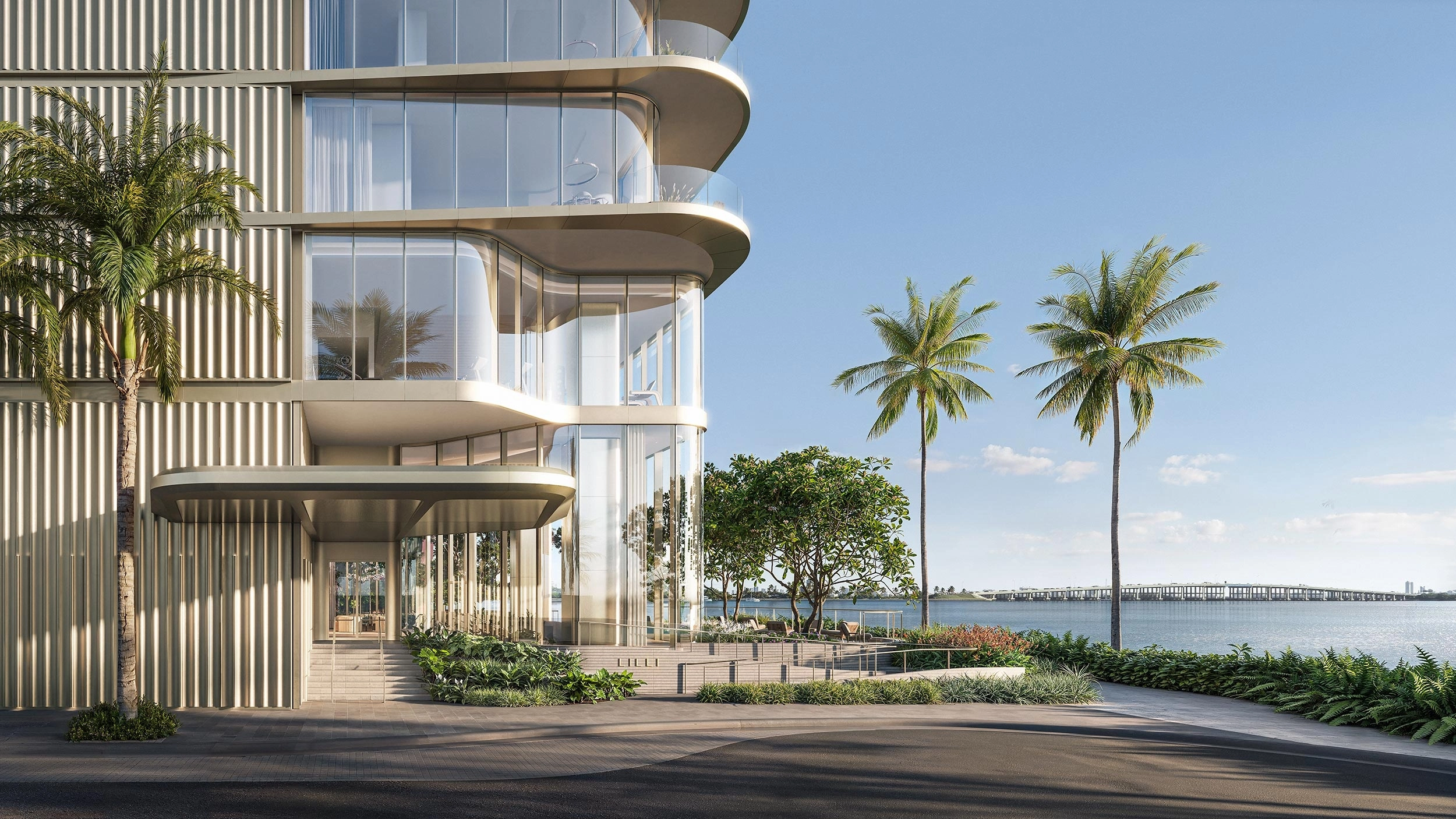 Modern luxury Edgewater Miami condos: LILLI entrance with curved glass balconies, palm trees & bridge over Biscayne Bay.